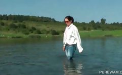 Clothed slut sensually touching wet body in the lake